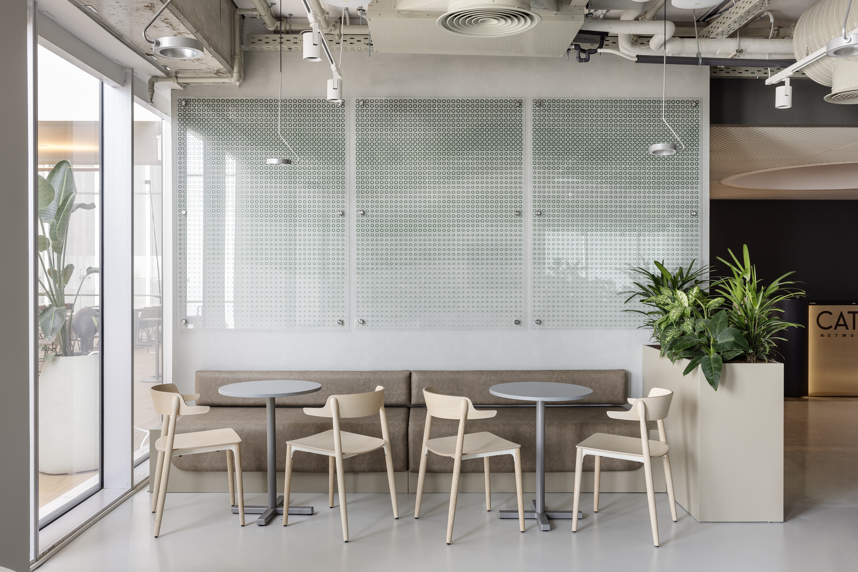 Cafeteria seating beneath three glass panels printed with the brand-pixel pattern.