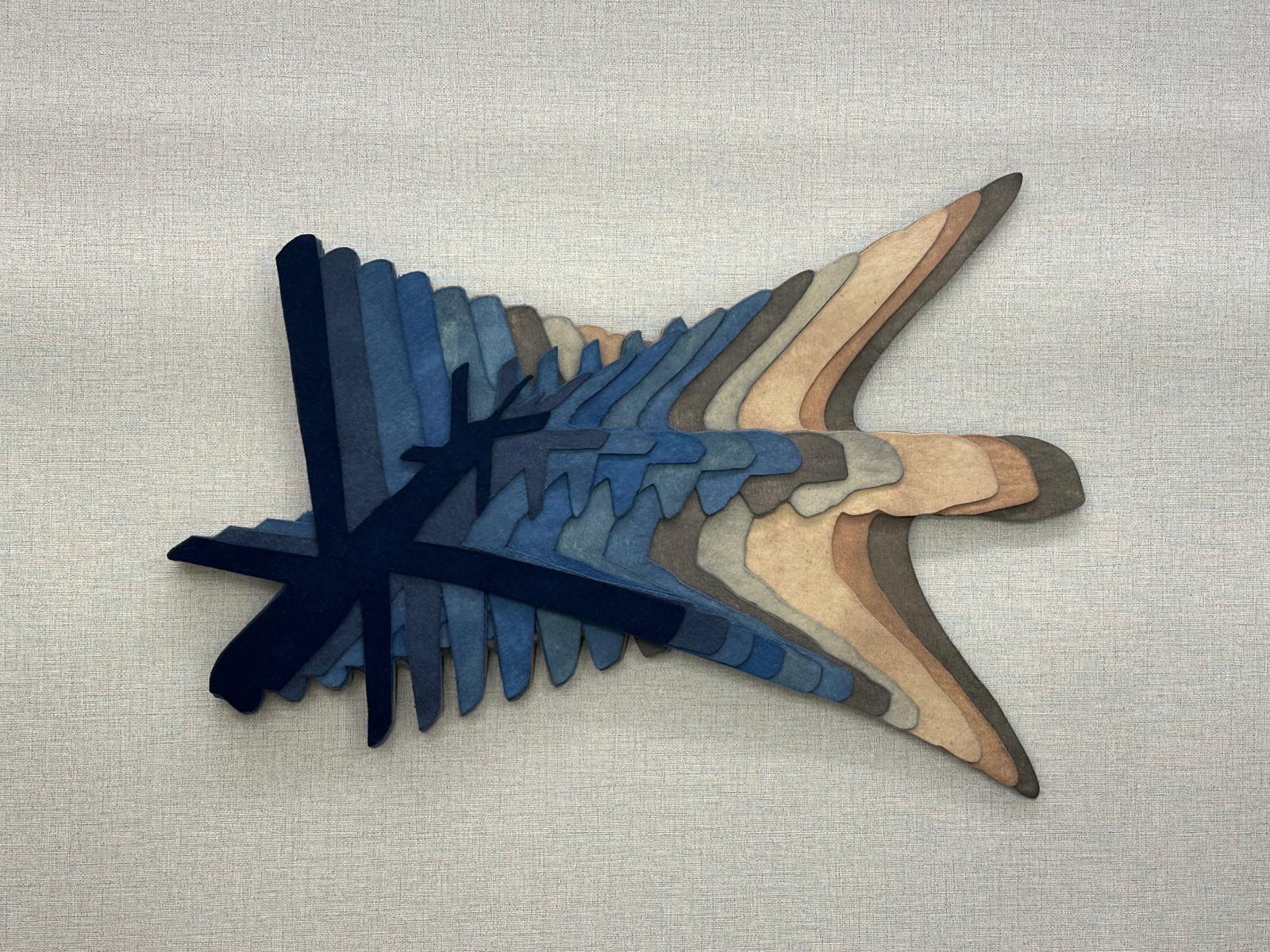 A UAV in hand-dyed layered felt — indigo strata fading into sand, like terrain read from above.