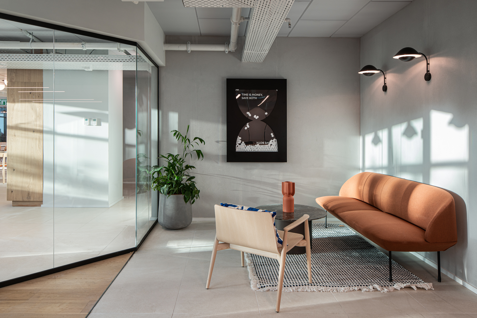 The value-art gallery wall — a “Time is money, save both” piece beside the orange lounge sofa.